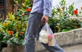 Yuong man carrying snacks of coffee and bread in throw-away plastic shopping bags.