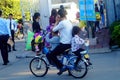Shenzhen, China: a young father riding a bicycle carrying a little girl home from kindergarten