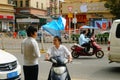 Shenzhen, China: a young woman riding an electric car chats with a man on the road