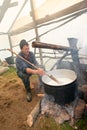 Shepherd boiling milk for cheese making at the farm in Transylvania Roumania