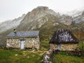 Shepherd huts in Lago del Valle with some snow in the mountains, Somiedo Natural Park and Biosphere Reserve, Asturias, Spain