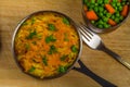 Shepherds or cottage pie in serving dish with parsley on wooden board