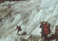 Sherpa porters carry loads beneath huge glacier