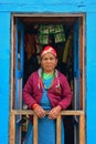 Nepalese Sherpa woman in traditional attire standing at front blue door along Everest Base Camp village, Nepal Royalty Free Stock Photo