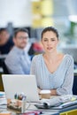 Shes ahead of the office curve. Portrait of a designer sitting at her desk working on a laptop with colleagues in the