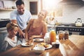 Shes an amazing mother and care-giver for our family. a little boy eating breakfast with his parents.