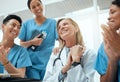 Shes the best mentor to look up to. a group of doctors clapping hands in a meeting at work.