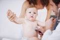 Shes a compliant little patient. A baby girl being examined by a doctor while her mother stands in the background. Royalty Free Stock Photo