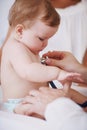 Shes curious about this examination. A baby girl being examined by a doctor while her mother stands in the background.