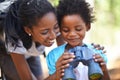 Shes a curious little one. a mother and daughter holding binoculars while out for a day in the forest.