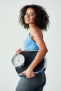 Shes determined to change the number on the scale. Studio shot of an athletic young woman holding a scale against a grey Royalty Free Stock Photo