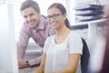 Shes doing great. a handsome young man helping a female coworker on her computer.