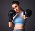 Shes fiercer than you think. Portrait of a young woman wearing boxing gloves against a grey background.