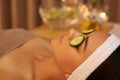 Shes found her paradise. A beautiful young woman lying on a massage table at the spa with cucumer over her eyes.