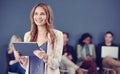 Shes full of ambition. an attractive young businesswoman using a tablet with her colleagues in the background.