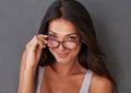 Shes giving you the eye. Studio shot of an attractive young woman peering over her glasses. Royalty Free Stock Photo