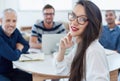 Shes a go getter. Portrait of a young office worker sitting at a table with colleagues in the background.