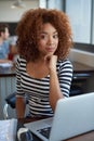 Shes a go getter. Portrait of a young woman working on a laptop in an office with a colleague in the background.