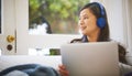 Shes got all her entertainment covered for the weekend. an attractive young woman wearing headphones while using a Royalty Free Stock Photo
