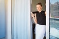 Shes got a busy day ahead of her. a young woman using her cellphone on the balcony of her hotel room.