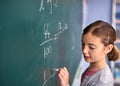 Shes almost got it. an elementary school girl writing on a blackboard in class. Royalty Free Stock Photo