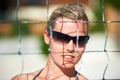 Shes got her sights set on a win. Portrait of an attractive woman standing behind a net wearing sunglasses.