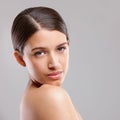 Shes got perfect skin. Portrait of a beautiful young woman looking over her shoulder against a gray background. Royalty Free Stock Photo