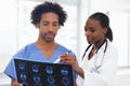 Shes great at explaining the scans. a female African American doctor and male nurse studying a CAT scan.