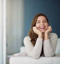 Shes a happy couch potato. Portrait of a happy young woman relaxing on the couch at home.