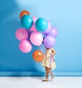 Shes a hidden cutey. a cute little girl standing behind a bunch of balloons.