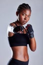 Shes more powerful than you think. Studio portrait of a sporty young woman wearing gloves and punching against a grey