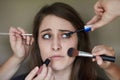 Shes not sure about all this...Concept shot of a nervous looking young woman with an assortment of brushes applying Royalty Free Stock Photo