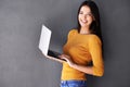 Shes an online social butterfly. Portrait of a beautiful young woman using a laptop against a gray background. Royalty Free Stock Photo