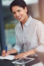 Shes a professional at problem solving. Portrait of a young businesswoman writing notes at an office desk.