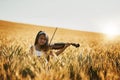 Shes in tune with nature. Portrait of a cute little girl playing the violin while standing in a cornfield. Royalty Free Stock Photo