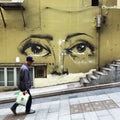 Sheung Wan, Hong Kong street art: man walking past mural Royalty Free Stock Photo