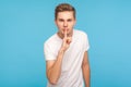 Shh, be quiet! Portrait of serious man in casual white t-shirt shushing to camera with finger on lips