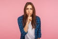 Shh, don`t speak! Portrait of worried unhappy girl in checkered shirt holding finger on lips showing silence gesture Royalty Free Stock Photo