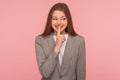 Shh, don`t tell anyone! Portrait of happy young woman in business suit smiling and holding finger on lips Royalty Free Stock Photo