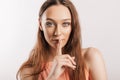 Shh gesture. Young beautiful serious girl holding a finger to her lips on a white isolated background. A woman asks to be silent, Royalty Free Stock Photo