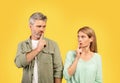 Shh, keep silence. Middle aged european couple gesturing hush sign, looking at each other and holding finger on lips Royalty Free Stock Photo
