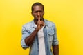 Shh, keep silence. Portrait of serious handsome man gesturing to be quiet. indoor studio shot isolated on yellow background Royalty Free Stock Photo