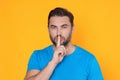 Shh man. Portrait of man showing shh taboo sign with finger to lips over yellow studio background. The secret. Hush shut Royalty Free Stock Photo