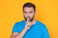 Shh man. Portrait of man showing shh taboo sign with finger to lips over yellow studio background. The secret. Hush shut Royalty Free Stock Photo