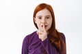 Shh this is secret. Cute redhead little girl, child shushing, show keep quiet taboo gesture, finger on lips, hushing Royalty Free Stock Photo