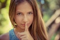 Shh. Woman wide eyed asking for silence secrecy with finger on lips hush hand gesture green park outdoor background Pretty girl