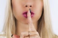 Shh! Women`s secrets. Beautiful blond Woman holding her finger to her pink lips in a gesture for silence. Making silence sign with Royalty Free Stock Photo