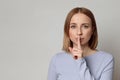 Shhh! European mysterious woman with short hair keep index finger over lips gesturing silence, isolated over grey background Royalty Free Stock Photo