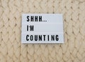 SHHH...I`M COUNTING word on lightbox on knit background. Cozy compozition. Knit WOOL background. Royalty Free Stock Photo