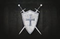 shield decorated with metal cross and two swords on dark background Royalty Free Stock Photo